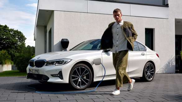 Plug-in hibrid, BMW 3 Limousine, 2021, G20, egy töltés alatt álló autó rézsútos elölnézetből Plug-in hibrid, BMW 3 Limousine, 2021, G20, egy modell társaságában látható, töltés alatt álló autó rézsútos elölnézetből