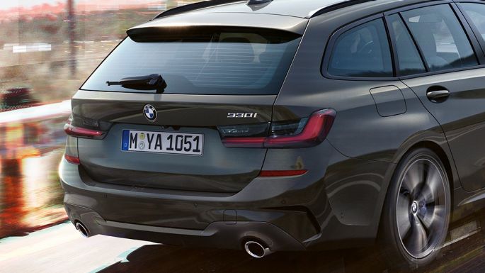 BMW 3-as Touring, háromnegyedes hátulnézet, dizájn Egy hídon áthaladó BMW 3-as Touring háromnegyedes hátulnézetből, vidéki tájjal a háttérben.