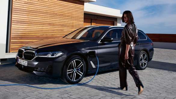 Plug-in hibrid BMW 5 Touring, 2021, G31, egy töltés alatt álló autó rézsútos oldalnézetből Plug-in hibrid BMW 5 Touring, 2021, G31, egy töltés alatt álló autó rézsútos oldalnézetből, egy modell társaságában