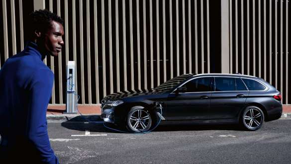 Plug-in hibrid BMW 5 Touring, 2021, G31, egy töltés alatt álló autó oldalnézetből Plug-in hibrid BMW 5 Touring, 2021, G31, egy oldalnézetből látható autó egy modell társaságában