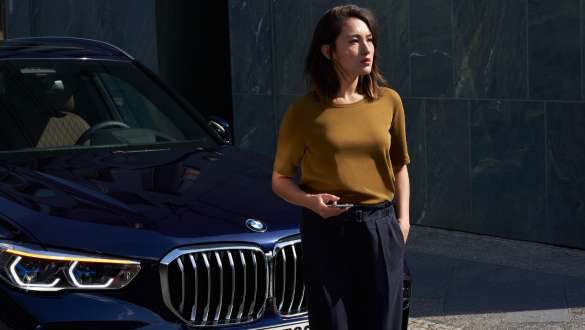 Egy nő áll egy BMW előtt BMW Országúti segélyszolgálat és vészhelyzetmenedzsment, egy nő áll egy BMW előtt