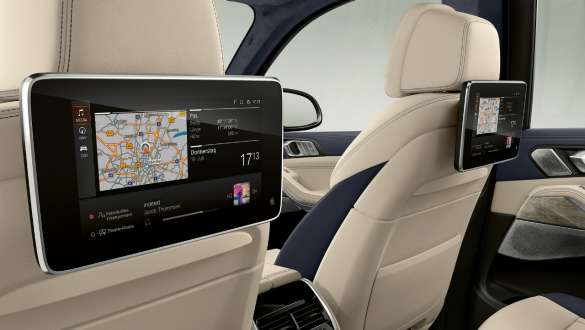 Egy BMW X7 M a Professional hátsó szórakoztató rendszerrel BMW X7 M, belső tér, az első ülések háttámlájára felszerelt Professional hátsó szórakoztató rendszer rézsútos oldalnézetből, G07