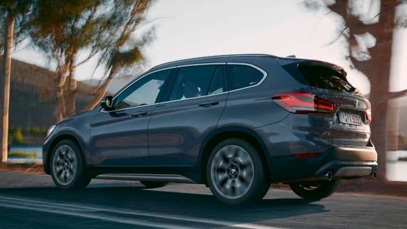 BMW X1, háromnegyedes hátulnézet. BMW X1, a mozgó autó háromnegyedes hátulnézetből, hegyvidéki tájjal a háttérben.
