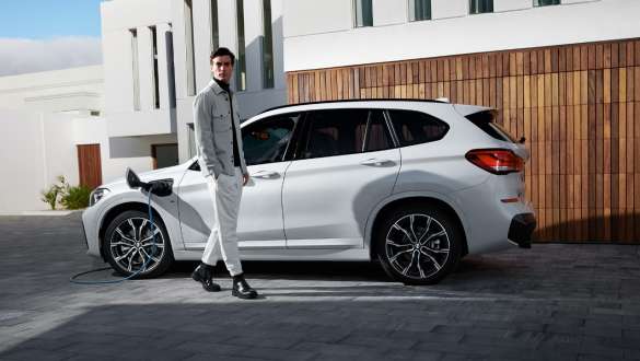 Plug-in hibrid, BMW X1 xDrive25e, F48, egy töltés alatt álló autó oldalnézetből Plug-in hibrid, BMW X1 xDrive25e, F48, egy modell társaságában látható, töltés alatt álló autó oldalnézetből