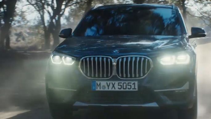 BMW X1, háromnegyedes elölnézet. BMW X1, a mozgó autó háromnegyedes elölnézetből, természeti környezetben.