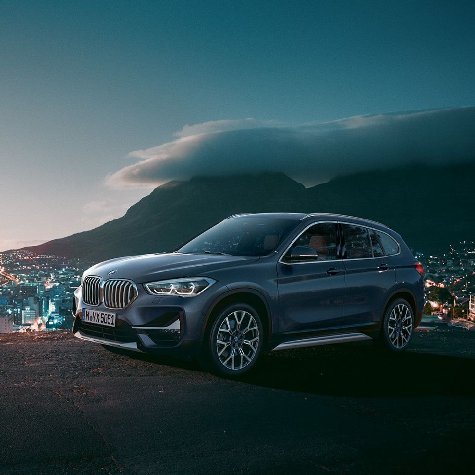 BMW X1, háromnegyedes oldalnézet. BMW X1, az álló autó rézsútos oldalnézetből, városi környezetben.