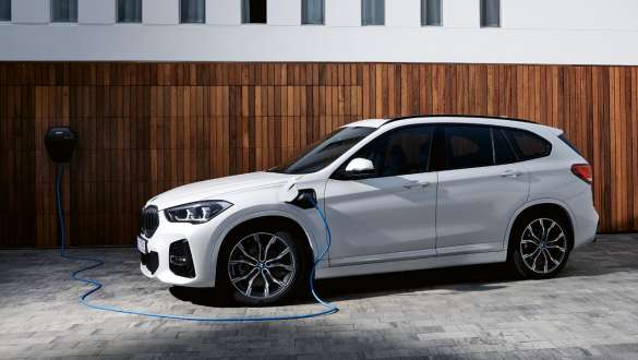 Plug-in hibrid, BMW X1 xDrive25e, F48 LCI, rézsútos oldalnézet Plug-in hibrid, BMW X1 xDrive25, F48 LCI, egy töltés alatt álló autó rézsútos oldalnézetből