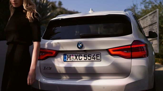 Far BMW i-specifikus diffúzorral, BMW iX3, G08, hátulnézet egy nővel Far BMW i-specifikus diffúzorral, BMW iX3, G08, 2020, egy Kristály fehér metálfényezésű autó hátulnézetből, egy nővel
