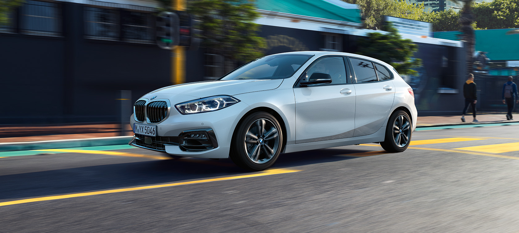 BMW 1-es, Sport Line modell, háromnegyedes oldalnézet. A BMW 1-es Kristály fehér metál Sport Line modellváltozata háromnegyedes oldalnézetből, mozgás közben.