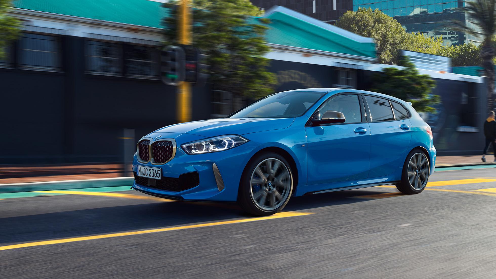 BMW 1-es, háromnegyedes oldalnézet. Egy Misano kék metál BMW 1-es mozgás közben, háromnegyedes elölnézetből.