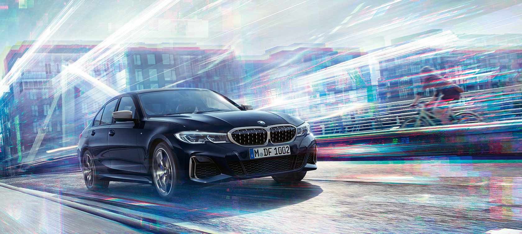 BMW 3-as Limousine, BMW M340i xDrive. Egy háromnegyedes oldalnézetből látható BMW M340i xDrive halad városi háttér előtt.