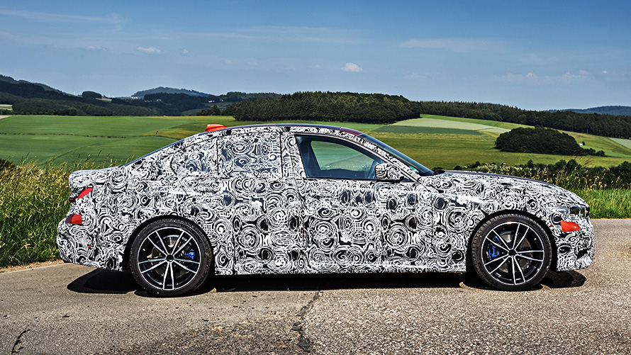 Akcióban a BMW 3-as. A BMW 3-as álcázott prototípusa oldalnézetből, a versenypálya kanyarjában.