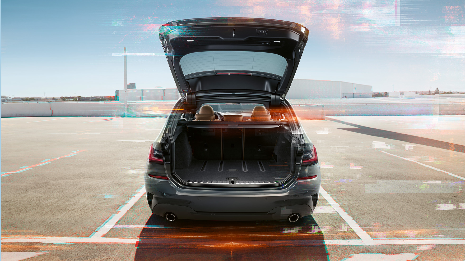 BMW 3-as Touring, hátulnézet nyitott csomagtérajtóval Egy nyitott csomagtérajtóval egy parkolóhelyen álló BMW 3-as Touring hátulnézetből, városi környezetben
