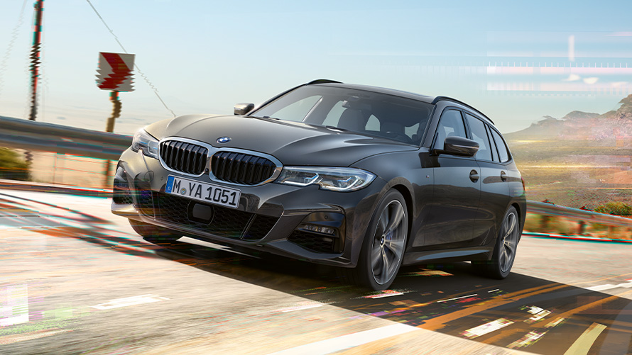 BMW 3 Touring (G21), Dravit szürke, rézsútos elölnézet BMW 3 Touring (G21), egy vidéki környezetben haladó, Dravit szürke autó rézsútos elölnézetből