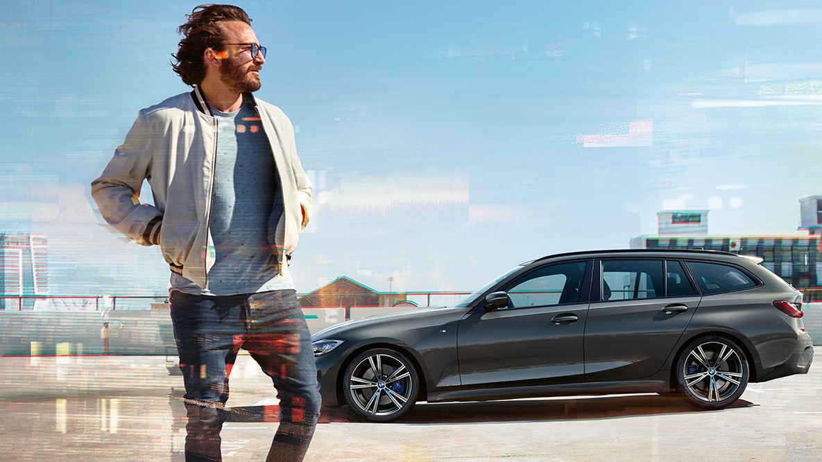 BMW 3-as touring (G21), rézsútos elölnézet, dizájn BMW 3 Touring (G21), egy vidéki környezetben álló hídon áthaladó, Dravit szürke autó rézsútos elölnézetből