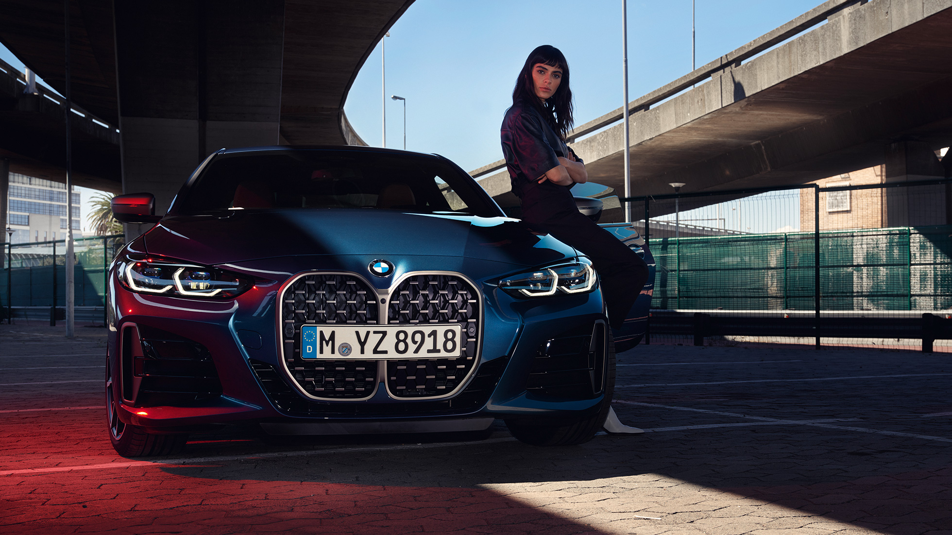 Orr-rész a dupla vesékkel és az első fényszórókkal, BMW 4 Coupé, G22, 2020 BMW 4 Coupé, G22, 2020, Arctic Race kék metál, egy modell társaságában látható autó orr-része a dupla vesével és az első fényszórókkal