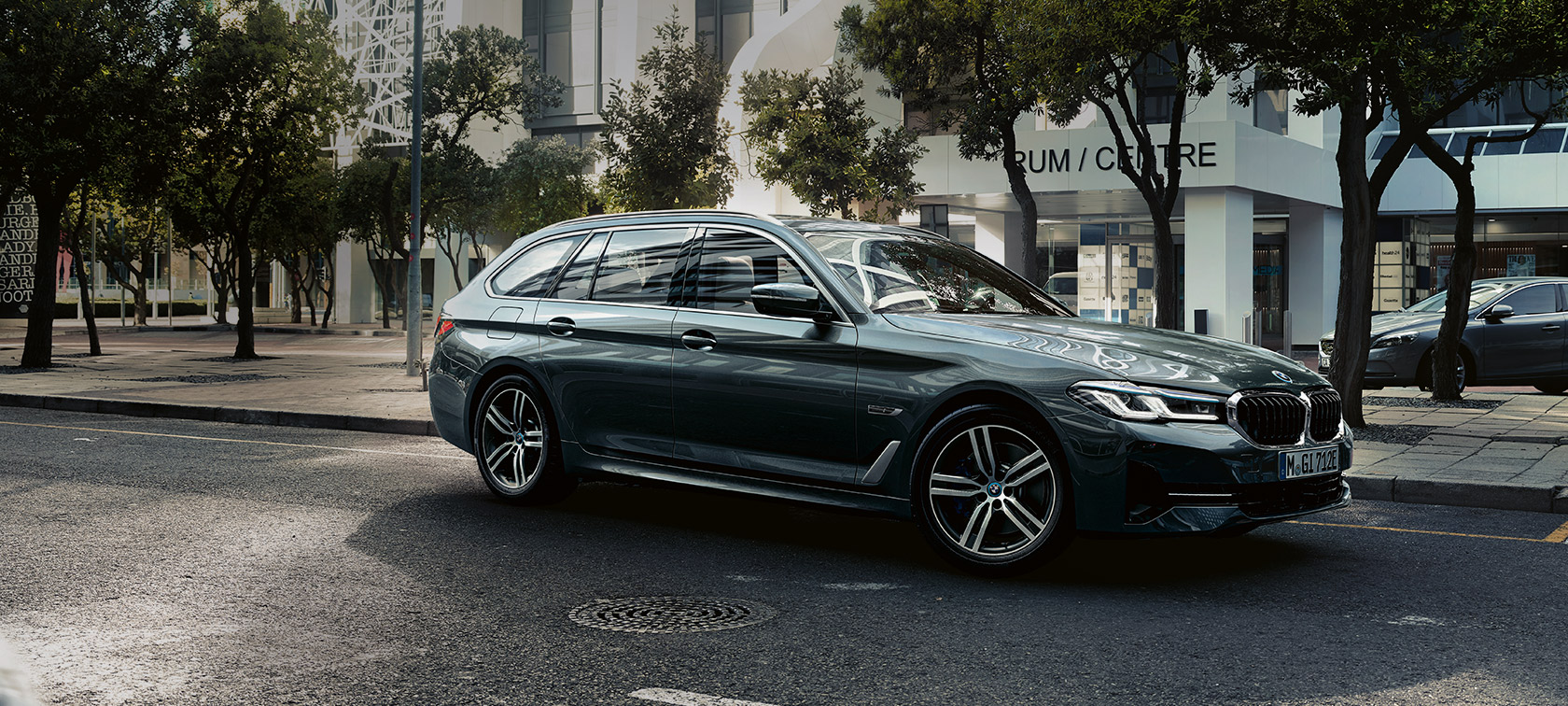 BMW 5 Touring, G31, Facelift 2020, egy Sophisto szürke, a külvárosban haladó rézsútos elölnézetből