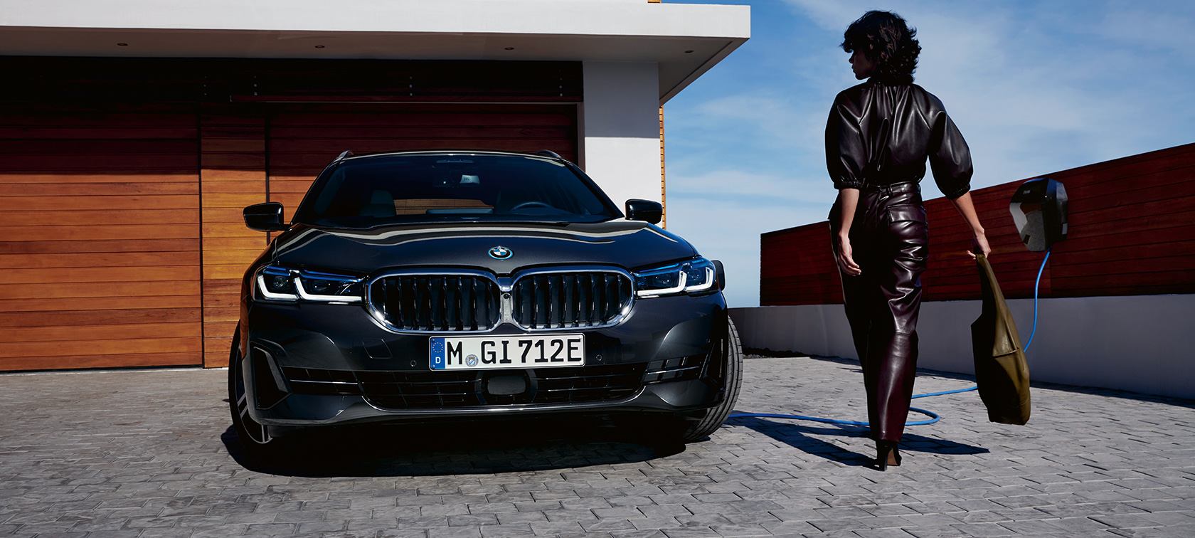 Plug-in hibrid, BMW 5 Touring, 2021, G31 LCI, egy töltés alatt álló autó elölnézetből Plug-in hibrid, BMW 5 Touring, 2021, G31 LCI, egy modell társaságában látható, töltés alatt álló autó elölnézetből