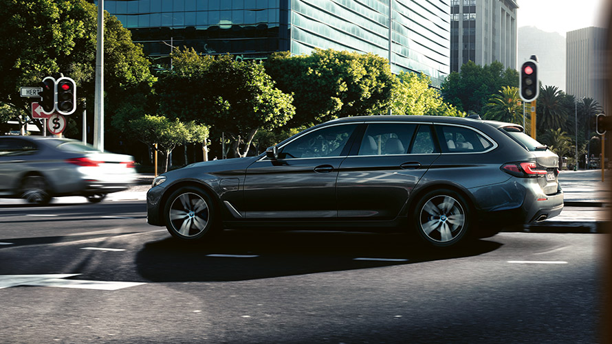 BMW 5 Touring, G31 LCI, egy városi forgalomban haladó, Sophisto szürke metálfényezésű autó BMW 5 Touring, G31 LCI, egy városi forgalomban haladó, Sophisto szürke metálfényezésű autó