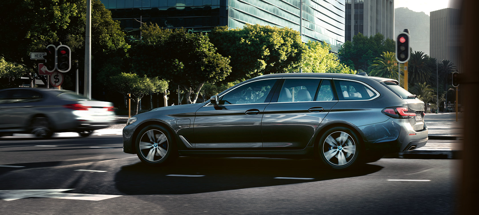 BMW 5 Touring, G31, LCI, egy épület előtt álló, Sophiso szürke metálfényezésű autó BMW 5 Touring, G31, LCI, egy épület előtt álló, Sophiso szürke metálfényezésű autó