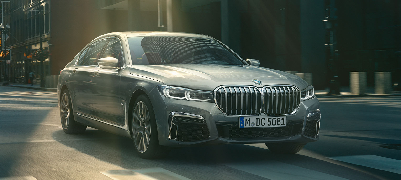 Szürke BMW 7-es Limousine, háromnegyedes elölnézet Egy szürke, városi környezetben haladó BMW 7-es Limousine háromnegyedes elölnézetből