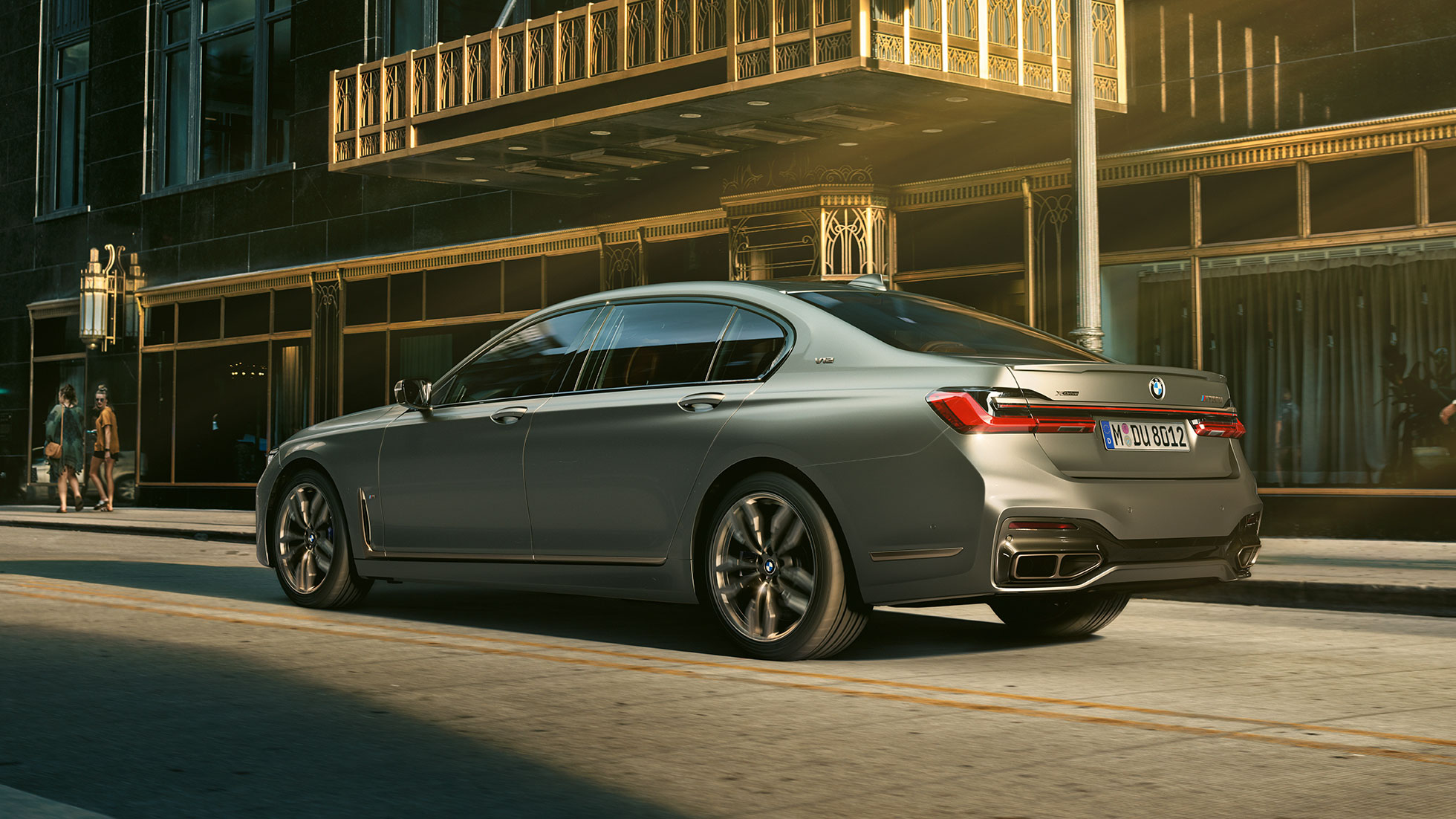 A V12-es motorral ellátott BMW M760Li xDrive Egy BMW M760Li xDrive rézsútos hátulnézetből, felhőkarcolós városi környezetben
