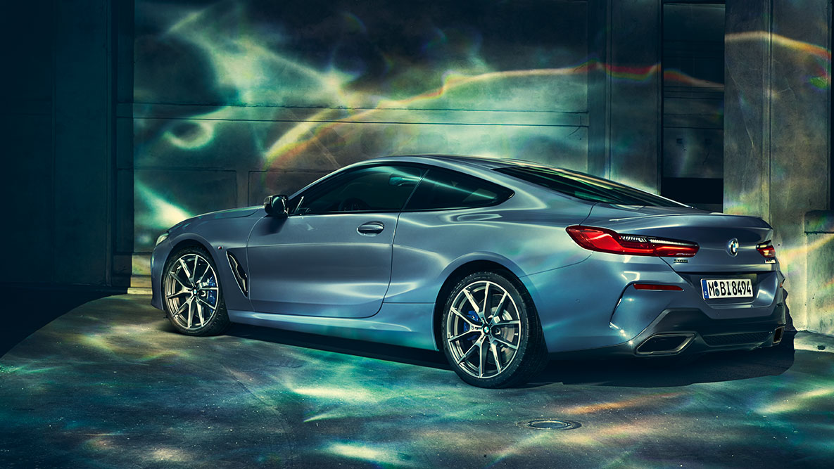 BMW 8 Coupé, háromnegyedes hátulnézet. A BMW 8 Coupé háromnegyedes hátulnézetből, éjszaka, városi háttér előtt.