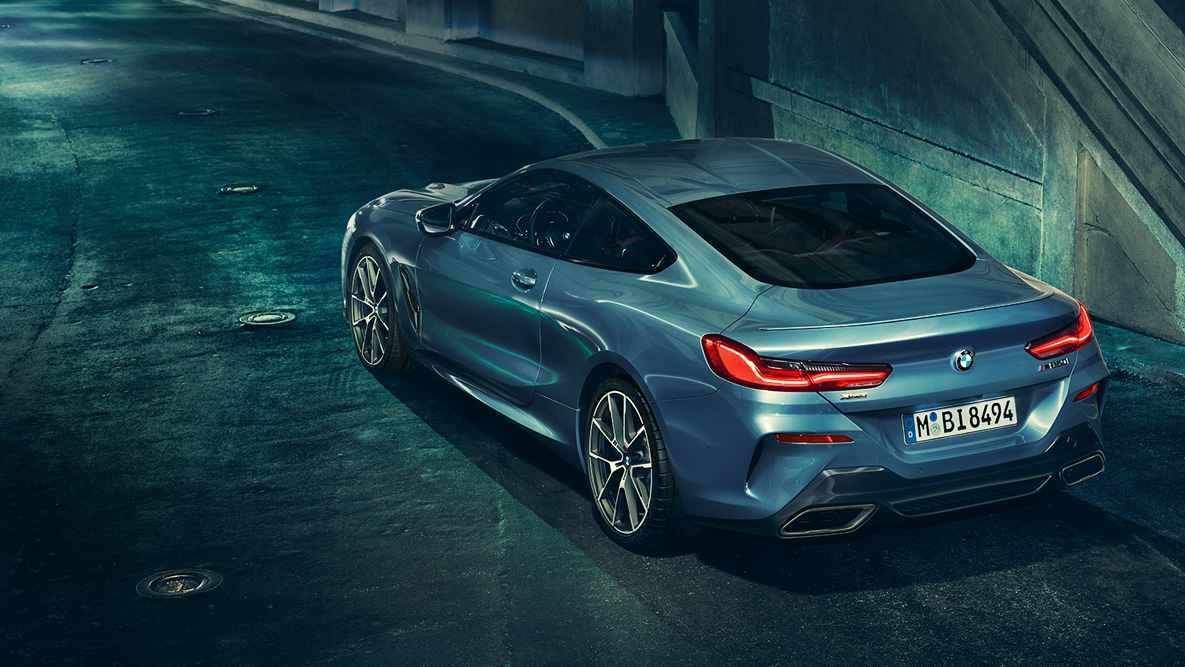 BMW 8 Coupé, háromnegyedes hátulnézet. A BMW 8 Coupé háromnegyedes hátulnézetből, éjszaka, városi háttér előtt.
