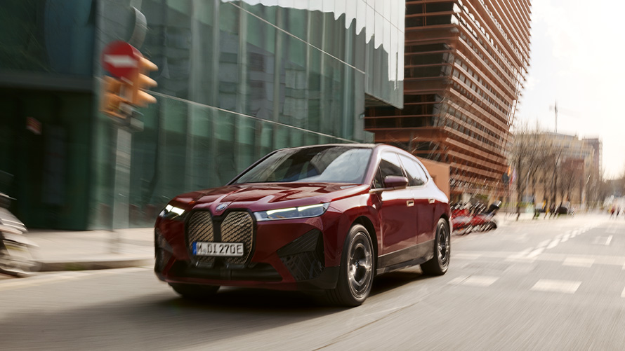 BMW iX, i20, elektromos SUV, BMW iX, xDrive50, vezetőt segítő rendszerek BMW iX, i20, 2021, elektromos SUV, BMW iX, xDrive50, egy városi környezetben haladó, Aventurin vörös fényezésű autó
