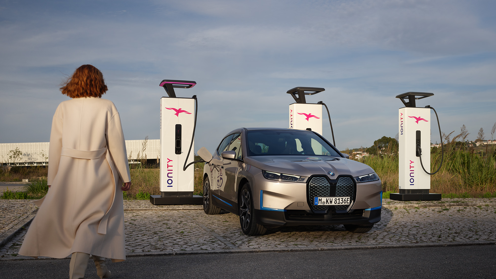 BMW iX, egy töltőállomáson álló autó rézsútos elölnézetből BMW iX, Kashmir ezüst, i20, egy töltőállomáson álló autó rézsútos elölnézetből