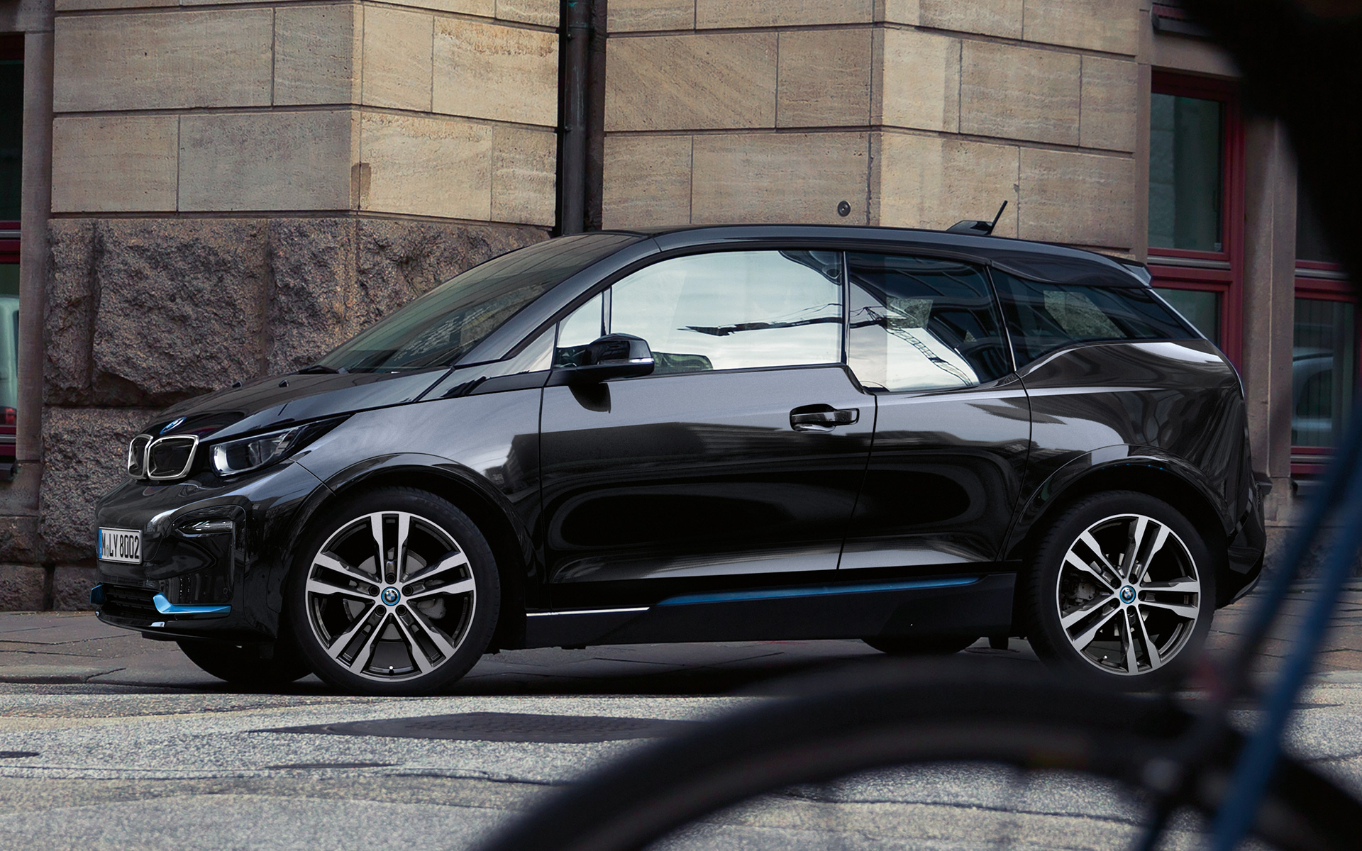 BMW i3s, I01, 2018, oldalnézet BMW i3s, I01, 2018, BMW i kék kiemeléssel ellátott Fluid fekete fényezés, egy városi környezetben haladó autó oldalnézetből