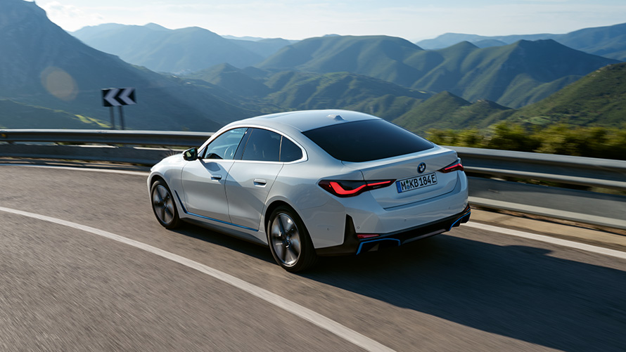 Egy mozgó BMW i4 eDrive40 rézsútos hátulnézetből, G26, 2021 BMW i4 eDrive40, G26, 2021, egy mozgó Kristály fehér autó rézsútos elölnézetből