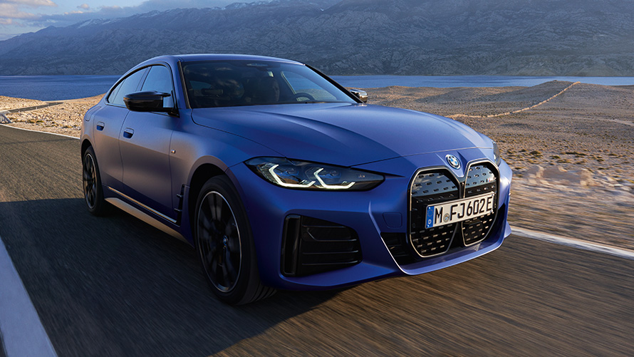 Rézsútos elölnézet, BMW i4 M50, G26, 2021 BMW i4 M50, G26, 2021, egy úton haladó, M Portimao kék metálfényezésű autó rézsútos elölnézetből