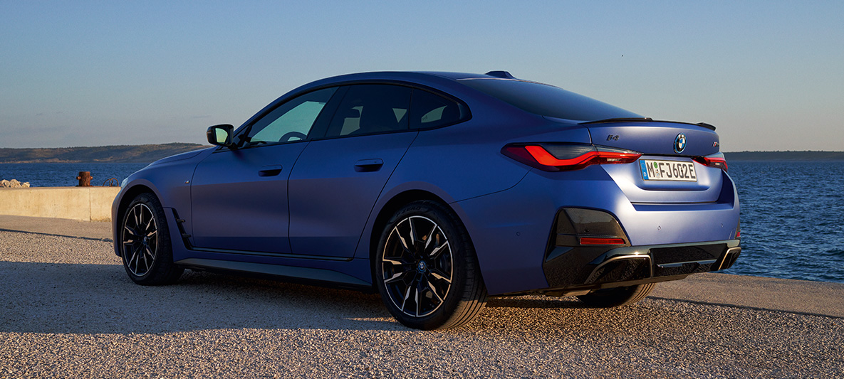 Rézsútos hátulnézet, BMW i4 M50, G26, 2021 BMW i4 M50, G26, 2021, egy rézsútos hátulnézetből látható, M Portimao kék metálfényezésű autó a gyártósoron