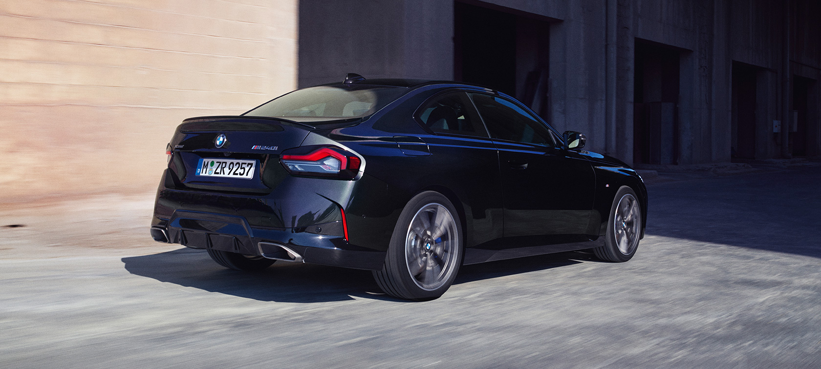 Rézsútos hátulnézet, BMW M240i xDrive Coupé, G42, 2021 BMW M240i xDrive Coupé, G42, 2021, egy mozgó, Zafírfekete metálfényezésű autó rézsútos hátulnézetből