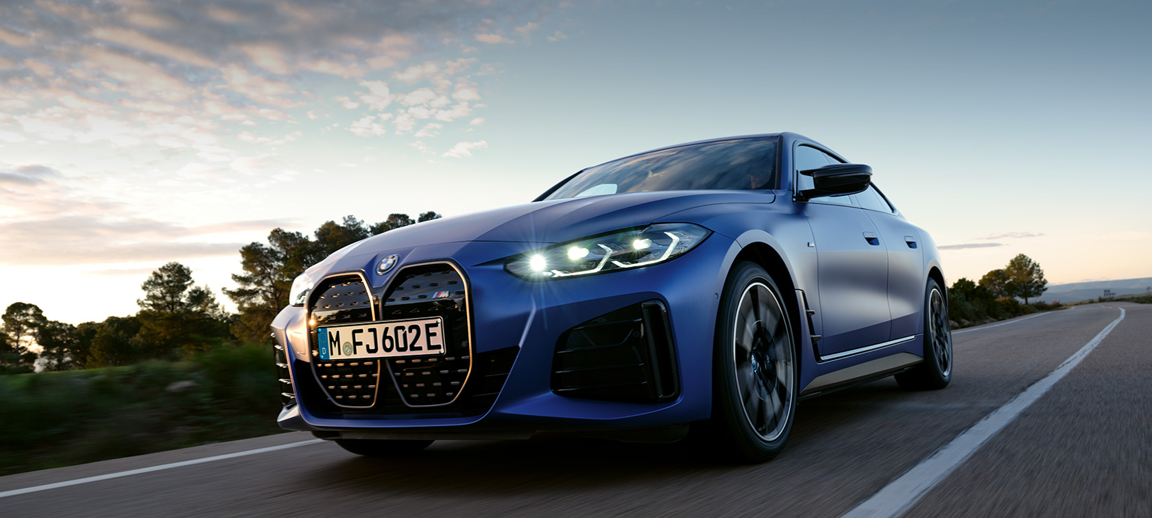 BMW i4 M50, G26, 2021, egy oldalnézetből látható autó köves tereppel a háttérben BMW i4 M50, G26, 2021, egy álló, BMW Individual Frozen Portimao kék metálfényezésű autó köves tereppel a háttérben
