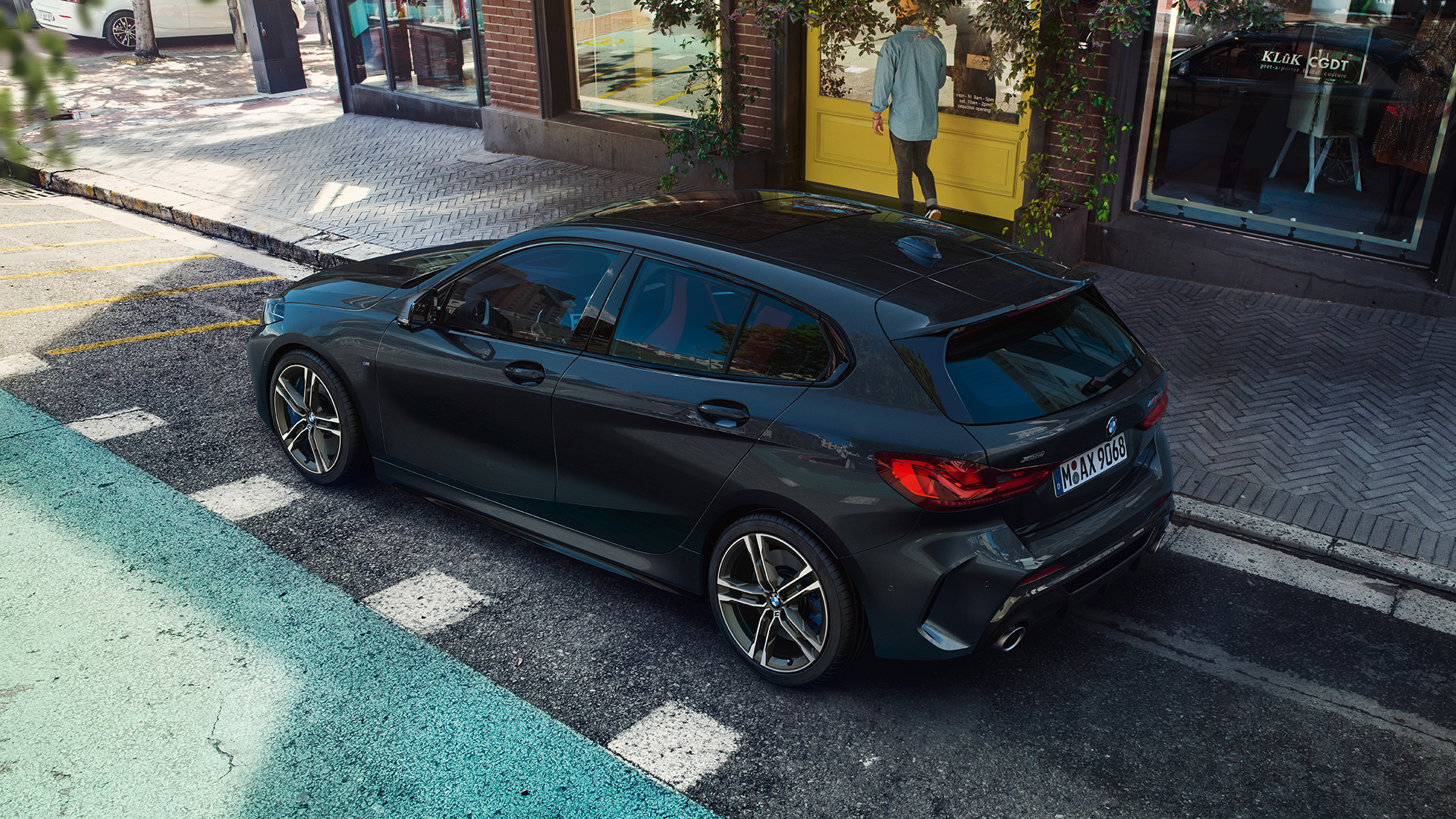 Egy álló BMW M135i xDrive. Egy álló, Zafírfekete metálfényezésű BMW M135i xDrive oldalról, felülnézetből.