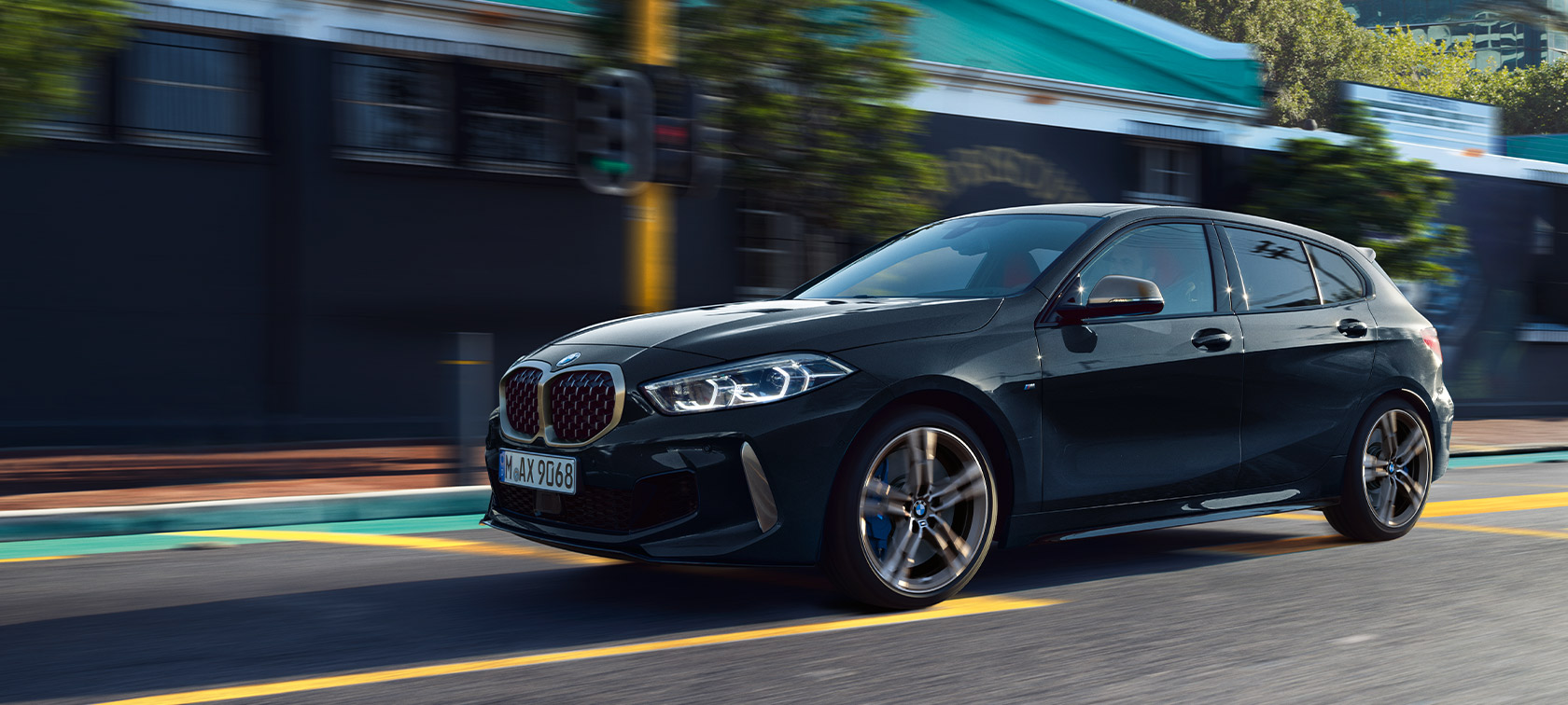 BMW 1, M135i xDrive (F40), egy városi környezetben haladó, Zafírfekete metál fényezésű autó