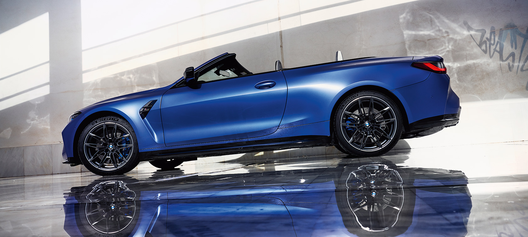 BMW M4 Competition Cabrio M xDrive-val, G83, 2021, egy álló autó oldalsó alulnézetből BMW M4 Competition Cabrio M xDrive-val, G83, 2021, BMW Individual Frozen Portimao kék metál, egy álló autó oldalsó alulnézetből