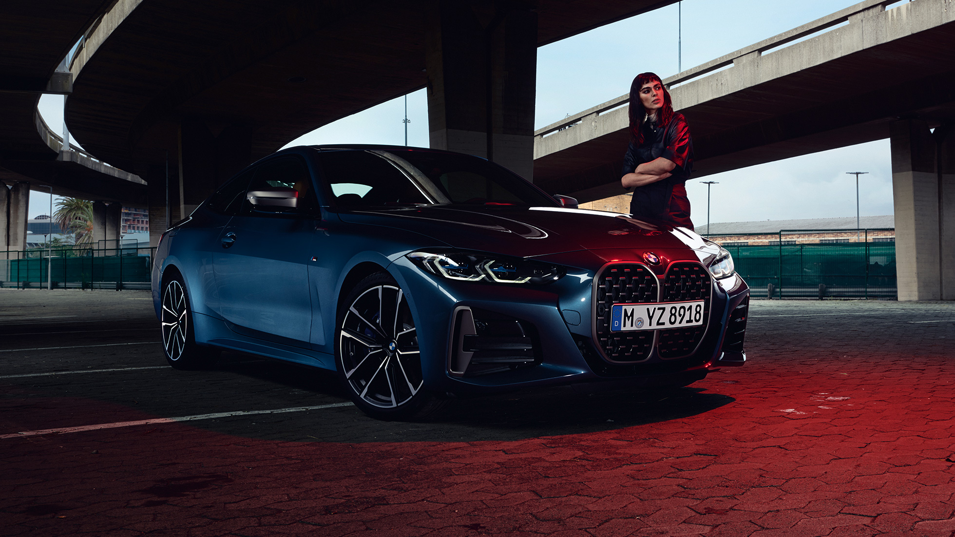 Egy modell áll egy BMW M440i xDrive Coupé mellett, G22, 2020, rézsútos oldalnézet BMW M440i xDrive Coupé, Arctic Race kék metál, G22, 2020, egy modell társaságában látható autó rézsútos oldalnézetből