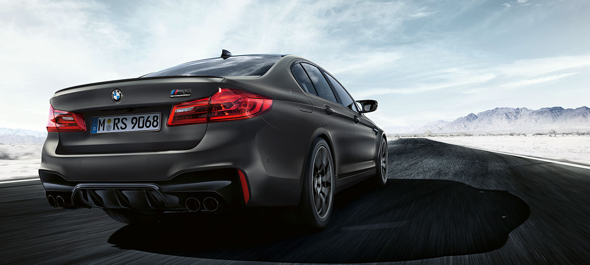 Kipufogók. Egy BMW M5 Edition 35 Years mozgás közben, háromnegyedes hátulnézetből.
