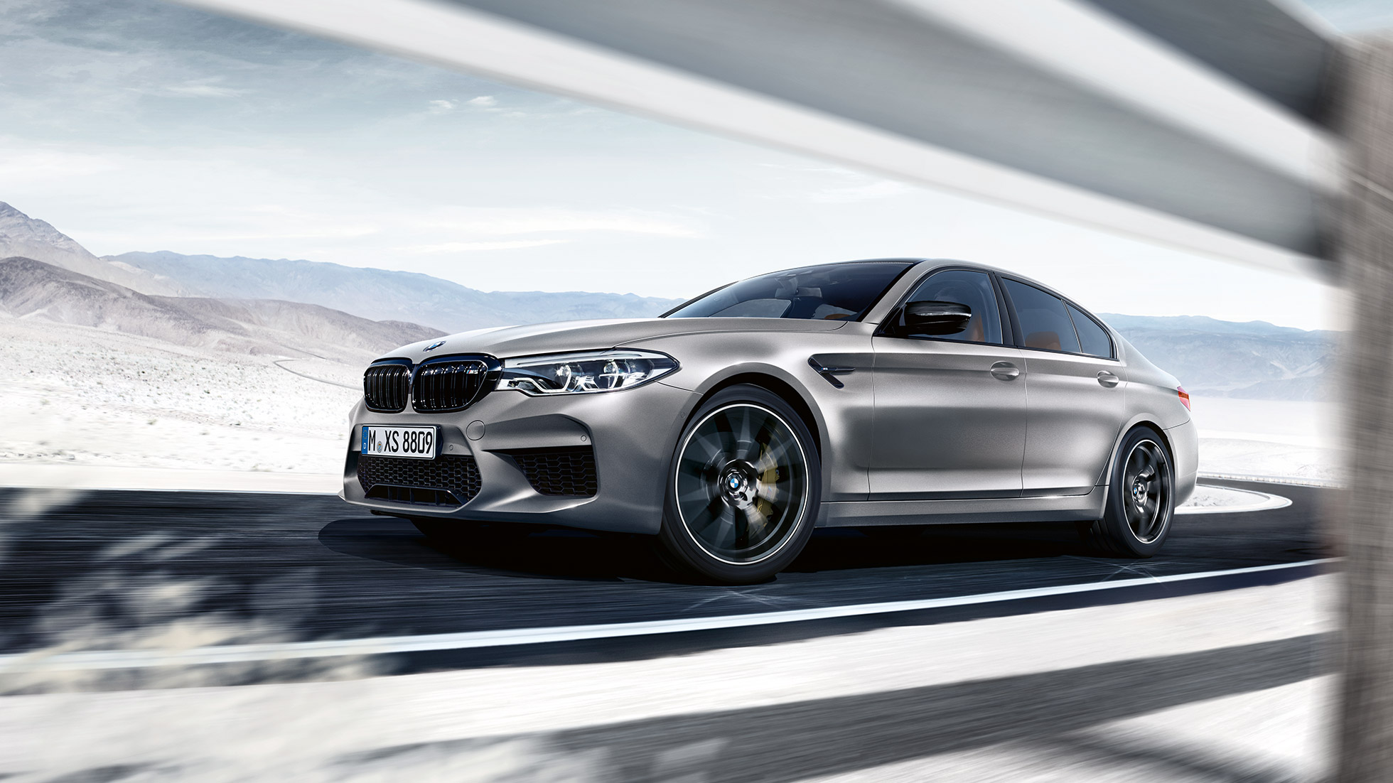 M xDrive. Egy mozgó BMW M5 Competition háromnegyedes elölnézetből.
