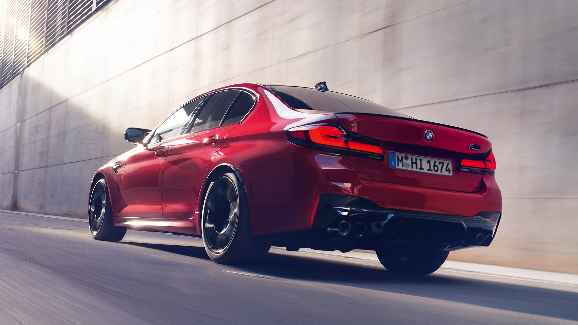 BMW M5 Competition, F90 LCI, Facelift 2020, rézsútos hátulnézet BMW M5 Competition, F90 LCI, Facelift 2020, egy mozgó BMW Individual Imola vörös autó rézsútos hátulnézetből