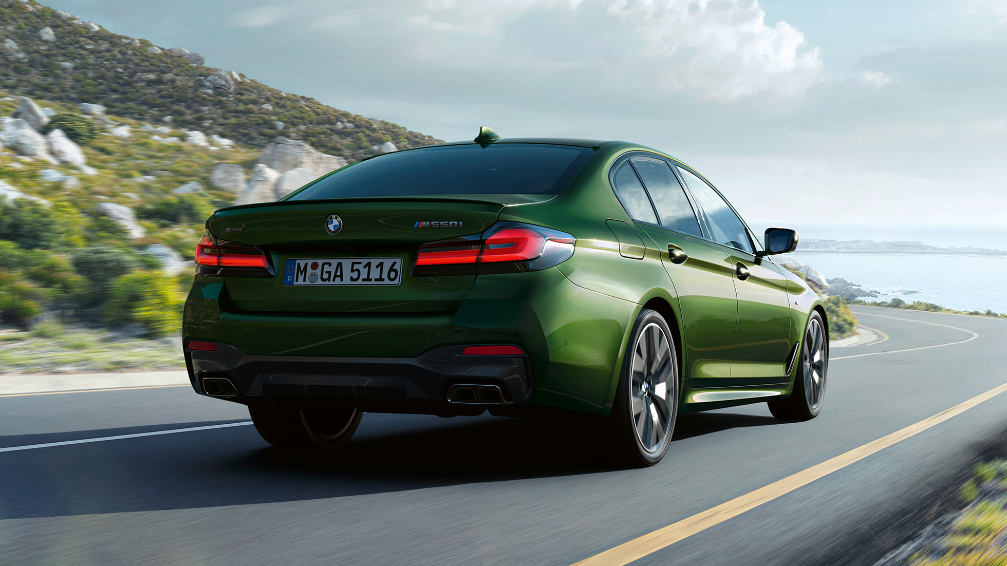 BMW M550i xDrive Limousine, G30 LCI, Facelift 2020, hátulnézet BMW M550i xDrive Limousine, G30 LCI, Facelift 2020, egy autópályán haladó BMW Individual Verde Ermes metálfényezésű autó hátulnézetből