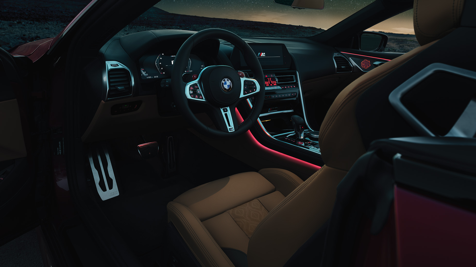 BMW M8 Cabrio, műszerfal. BMW M8 Competition Cabrio, a műszerfal éjszaka az M bőrkormánnyal és a vörös színű Hangulatvilágítással.