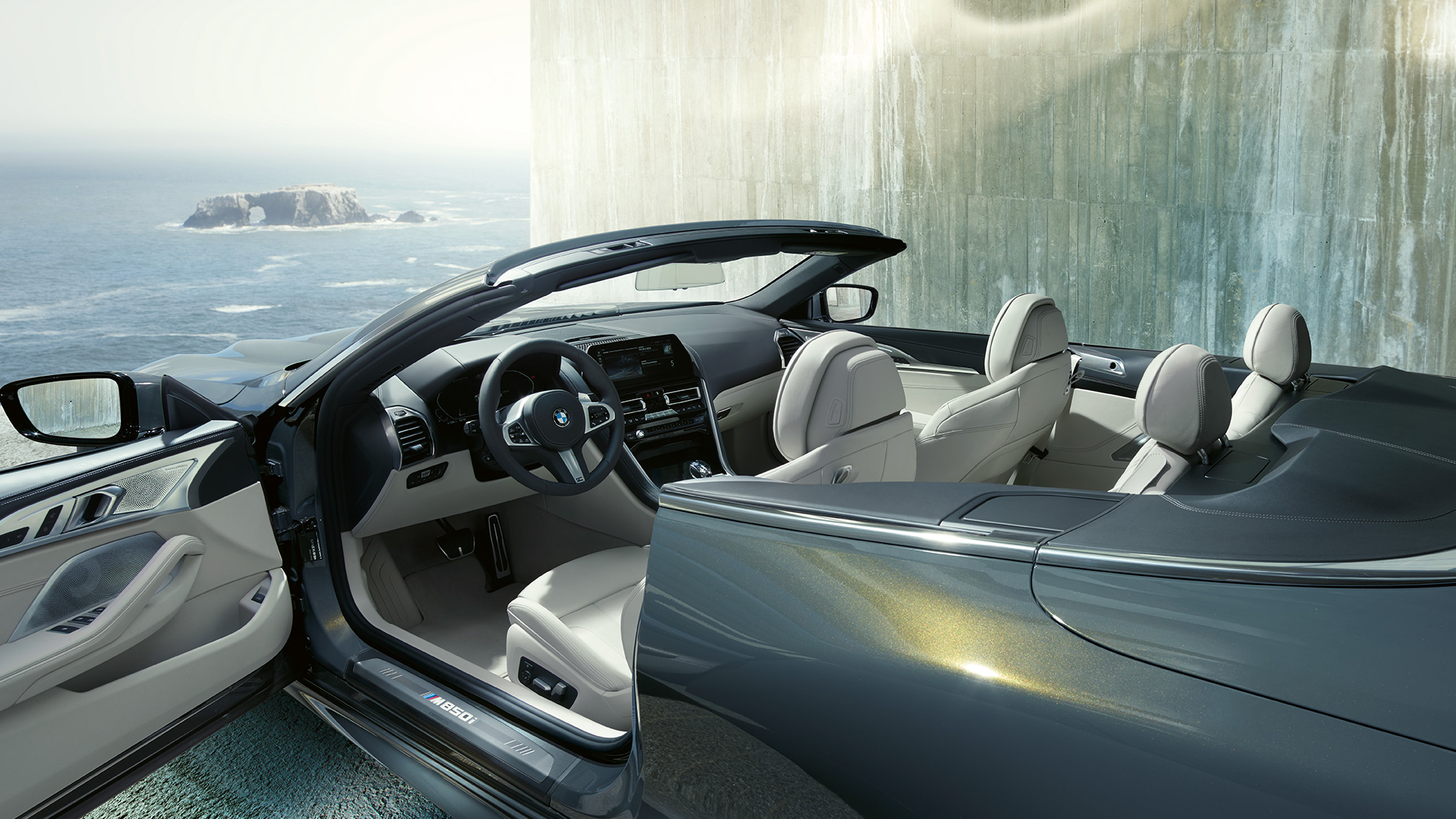 BMW M850i xDrive Cabrio, belső tér. Egy nyitott vászontetős, Dravit szürke metálfényezésű BMW M850i xDrive Cabrio belső tere az M bőrkormánnyal és az Elefántcsont BMW Individual Merino bőrkárpittal.