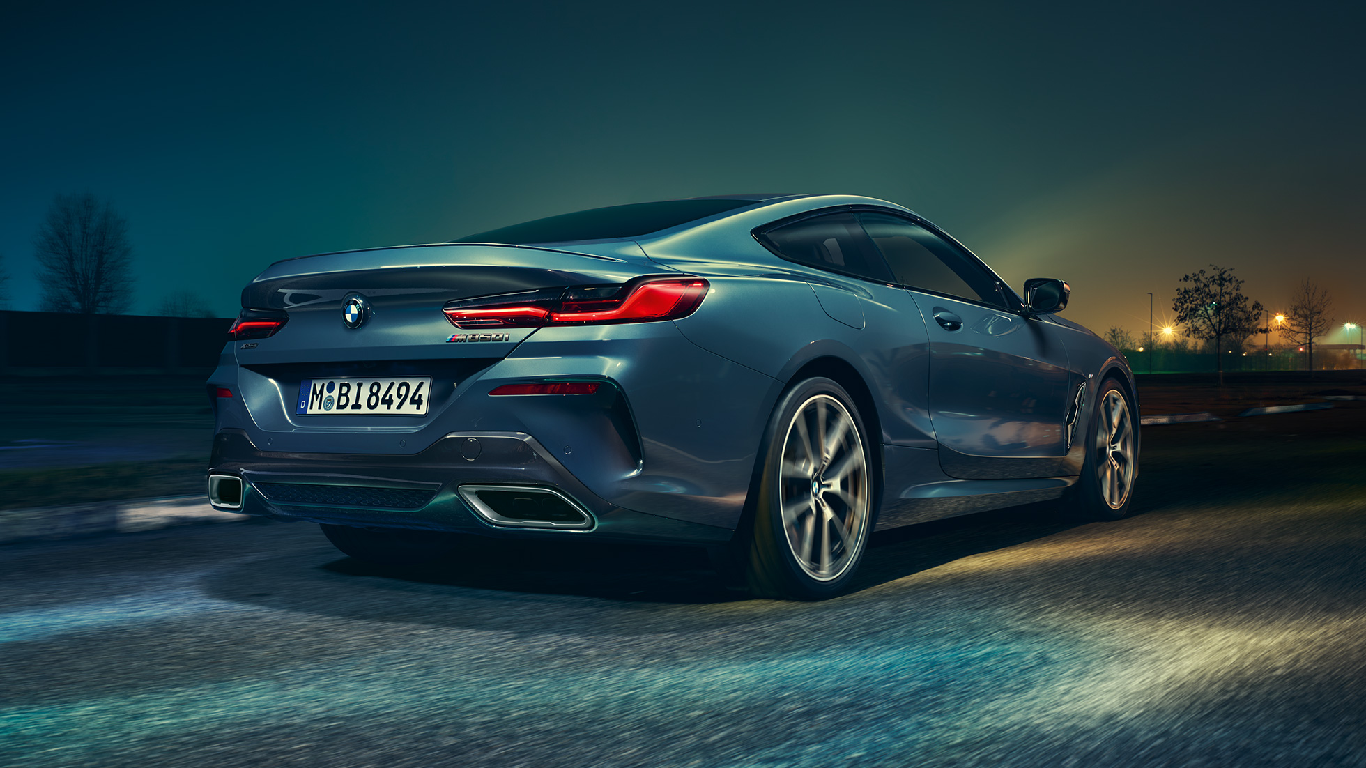 BMW M850i xDrive Coupé, hátulnézet. Egy mozgó, Barcelona kék metálfényezésű BMW M850i xDrive Coupé hátulnézetből, éjszaka.