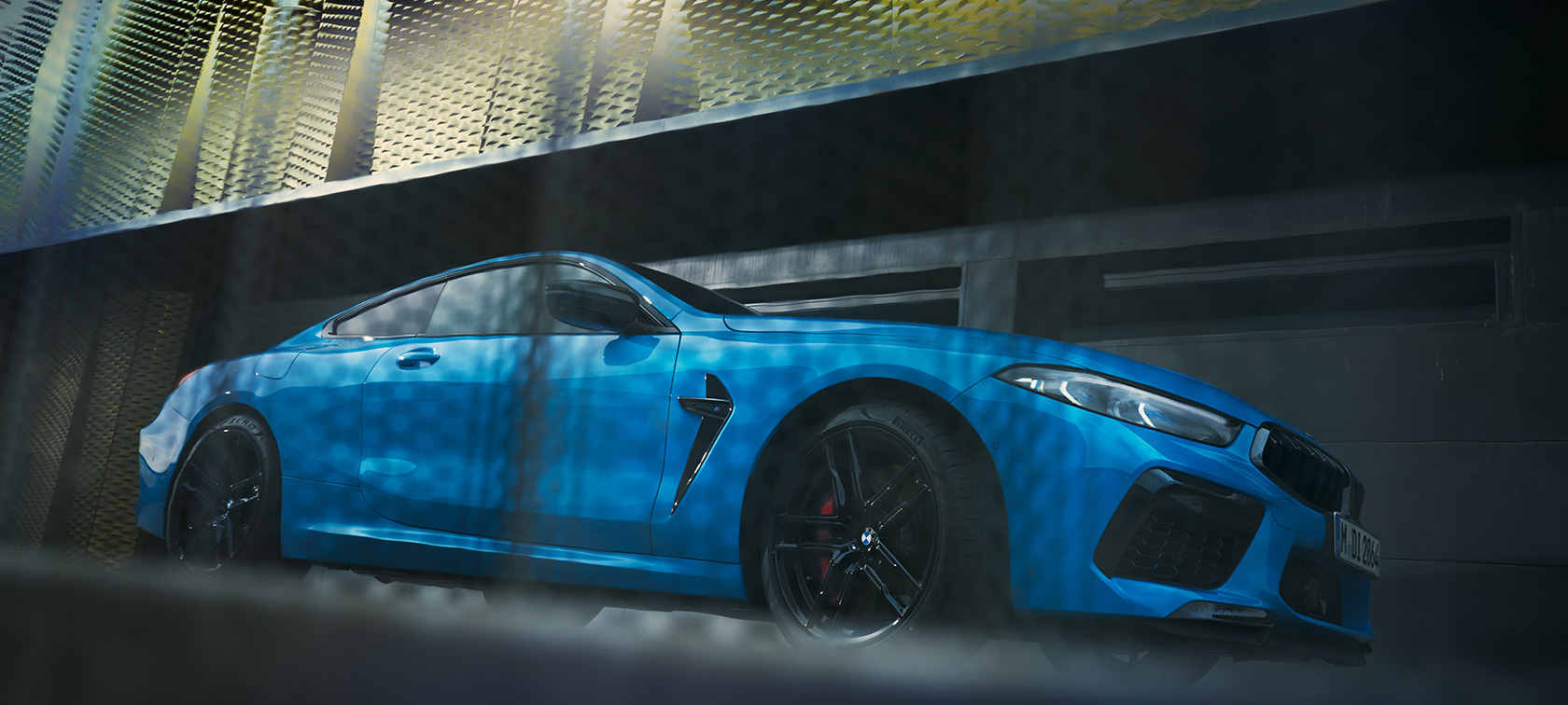 BMW M8 Competition Coupé, F92 LCI, Facelift 2022, egy álló autó alulsó oldalnézetből BMW M8 Competition Coupé, F92 LCI, Facelift 2022, egy épület előtt álló, BMW Individual Daytona Beach kék nem-metál fényezésű autó alulsó oldalnézetből