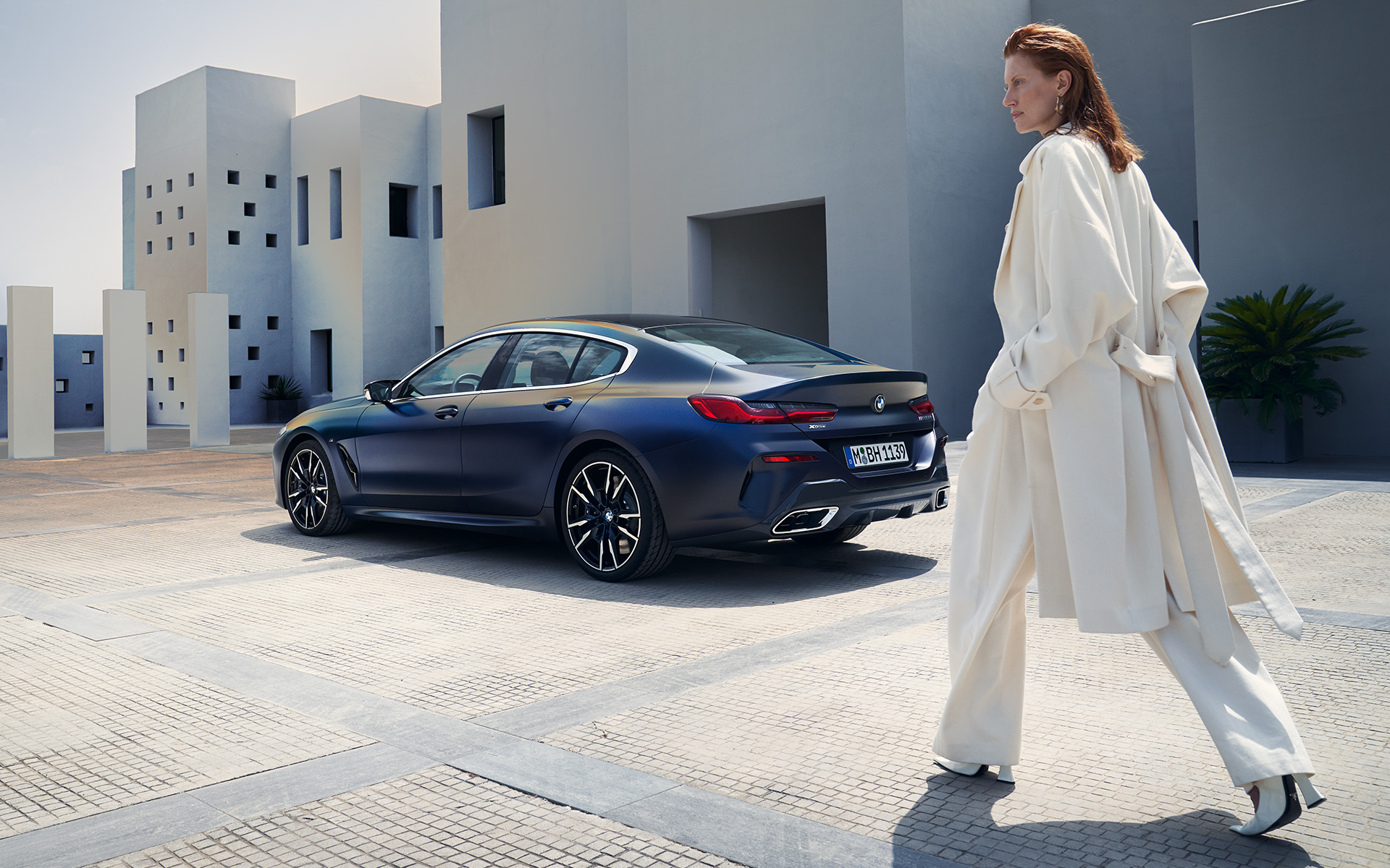 BMW M850i xDrive Gran Coupé, G16 LCI, Facelift 2022, egy oldalnézetből látható autó egy női modell társaságában BMW M850i xDrive Gran Coupé, G16 LCI, Facelift 2022, egy rézsútos hátulnézetből látható BMW Individual Frozen Tanzanit kék metálfényezésű autó egy női modell társaságában