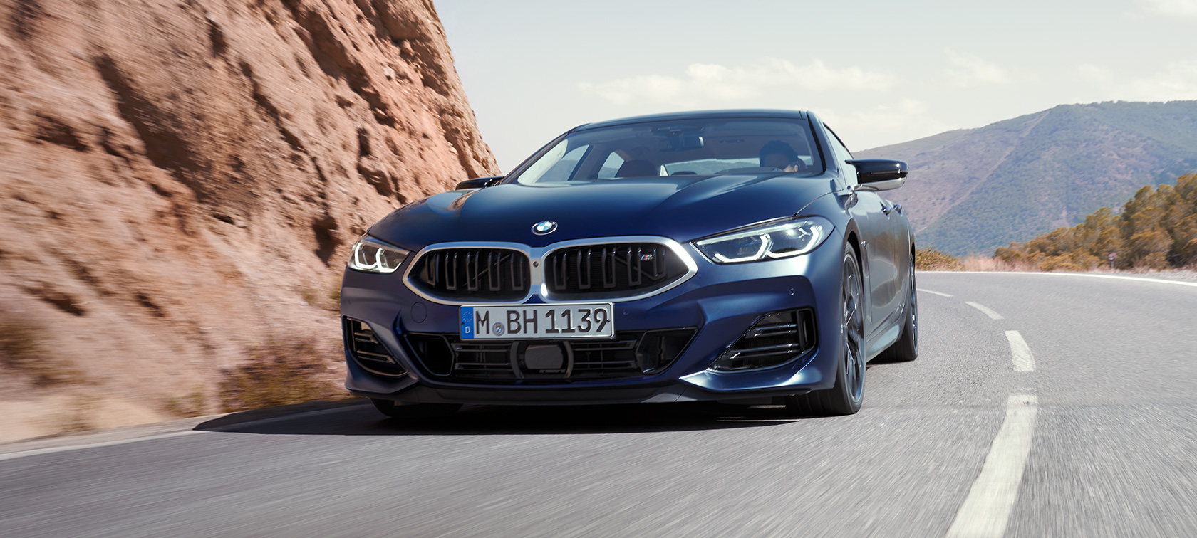 Rézsútos elölnézet, BMW M850i xDrive Gran Coupé, G16 LCI, Facelift 2022 BMW M850i xDrive Gran Coupé, G16 LCI, Facelift 2022, egy kanyarban haladó, BMW Individual Frozen Tanzanit kék metálfényezésű autó rézsútos elölnézetből